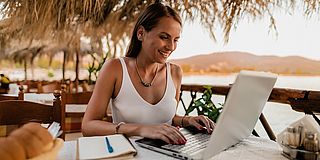 Frau mit Laptop arbeitet in Urlaubsregion